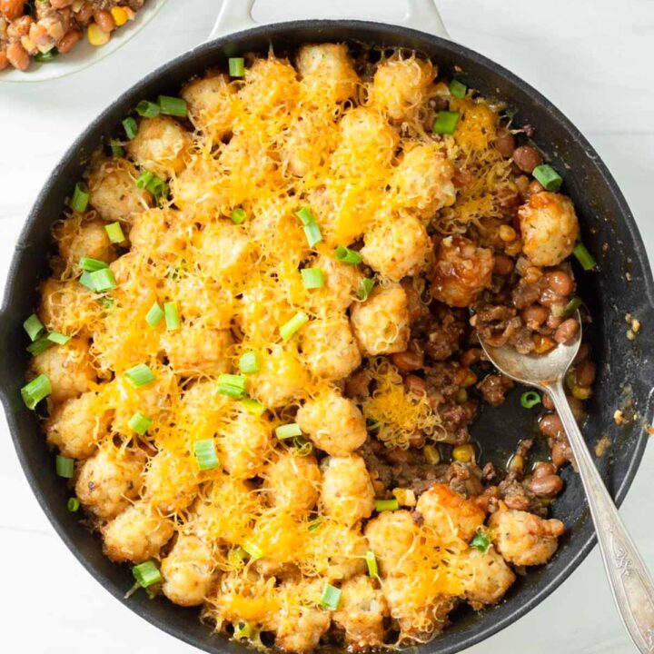 This cowboy tater tot casserole is an easy one-pan dinner recipe made with ground beef mixed with baked beans and corn and topped with cheese and tater tots. We love this easy kid-friendly dinner for a quick weeknight meal.