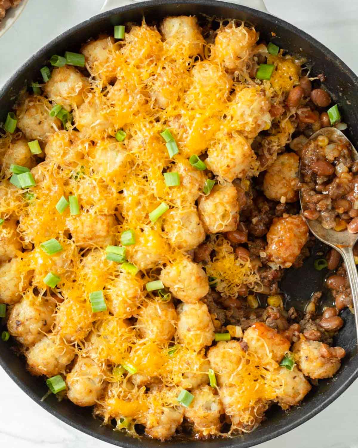 This cowboy tater tot casserole is an easy one-pan dinner recipe made with ground beef mixed with baked beans and corn and topped with cheese and tater tots. We love this easy kid-friendly dinner for a quick weeknight meal.