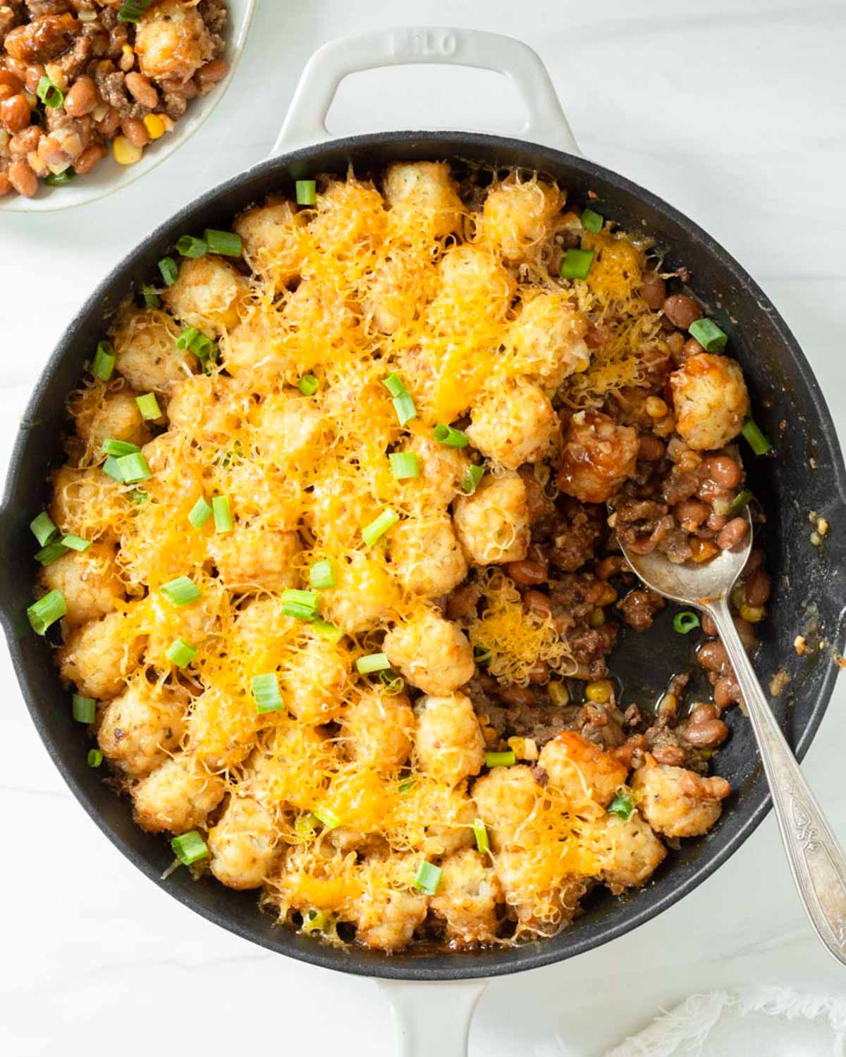 This cowboy tater tot casserole is an easy one-pan dinner recipe made with ground beef mixed with baked beans and corn and topped with cheese and tater tots. We love this easy kid-friendly dinner for a quick weeknight meal.