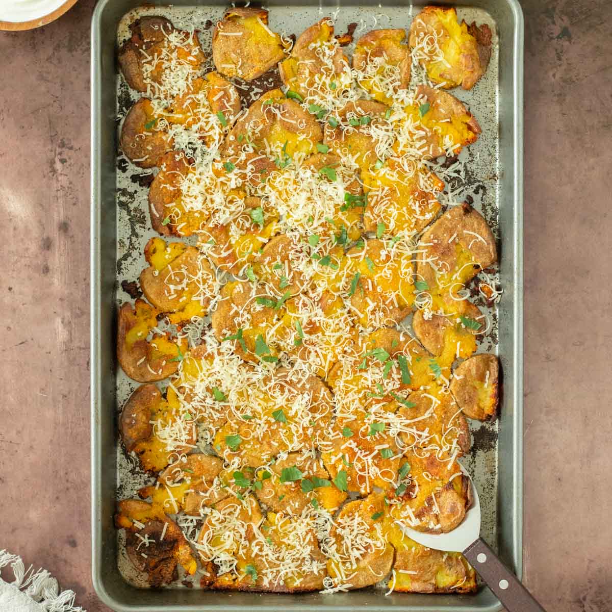 These garlic parmesan smashed potatoes are an easy and flavorful side dish perfect for a weeknight meal, holiday dinner, or as an appetizer. This smashed potato recipe makes crispy potatoes topped with simple spices for flavor and served with freshly grated parmesan cheese.