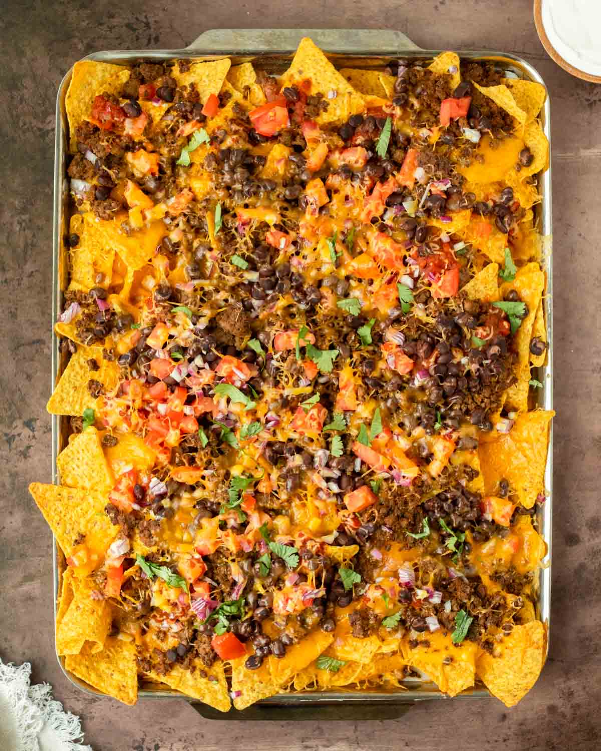 These sheet pan nachos are an easy appetizer recipe made with pantry-staple ingredients for a quick and flavorful crowd-pleaser dish. This recipe can be served for a game day appetizer but is also a great quick weeknight meal.