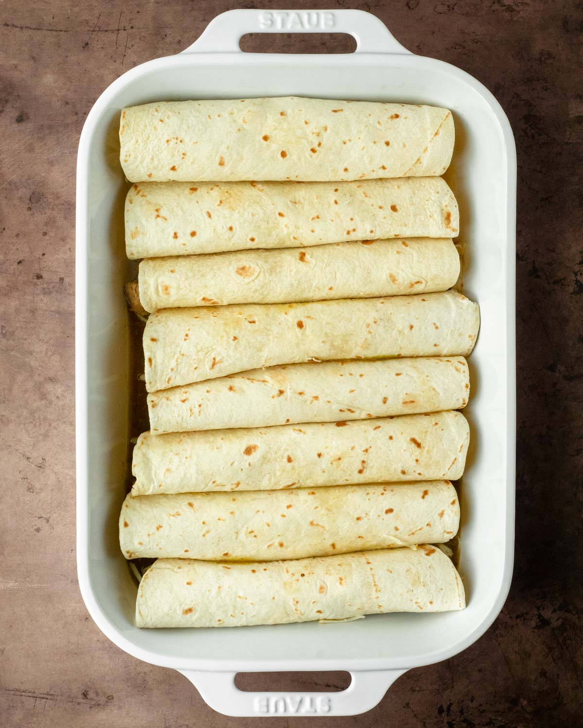 Step 1. Fill the tortillas with meat and cheese, roll up and place in the baking pan