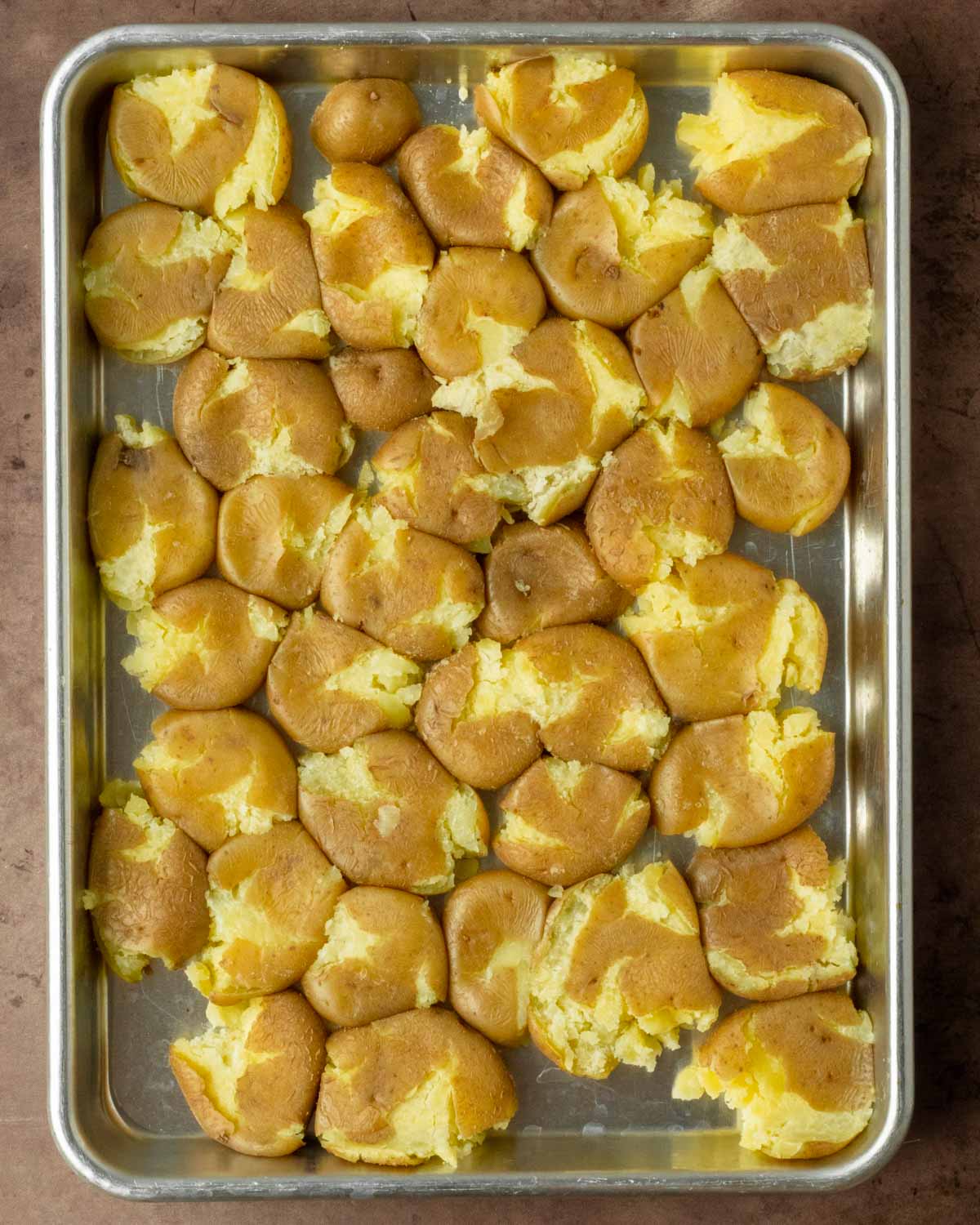 Step 1. Boil the potatoes, spread them out on a sheet pan and smash the potatoes