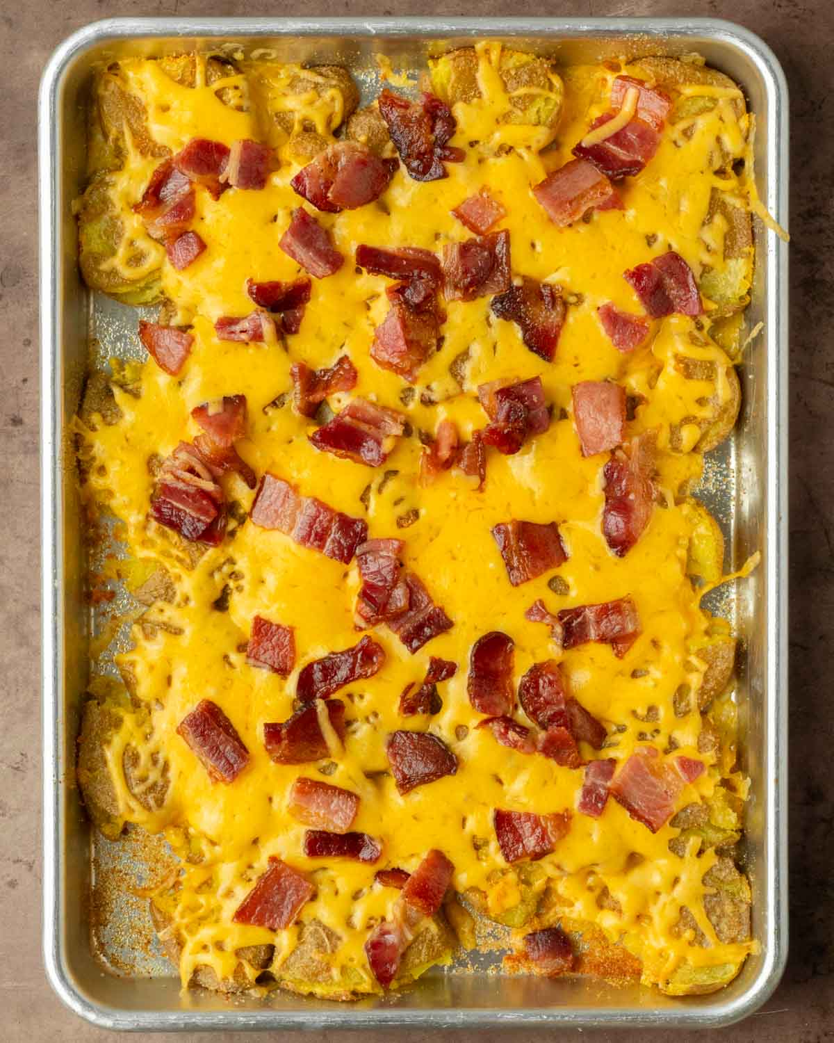 Step 3. Top the potatoes with cheese and bacon and place them back in the oven to finish baking
