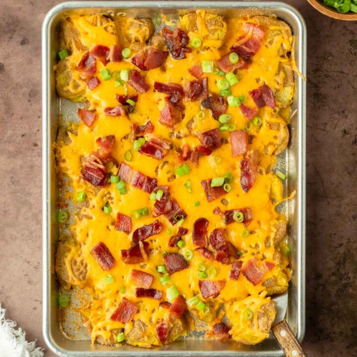 These twice baked smashed potatoes are everyone's favorite classic summer side dish made with crispy smashed potatoes baked on a sheet pan and topped with cheddar cheese and bacon. This recipe is perfect for a weeknight dinner side but also great to serve to a crowd.