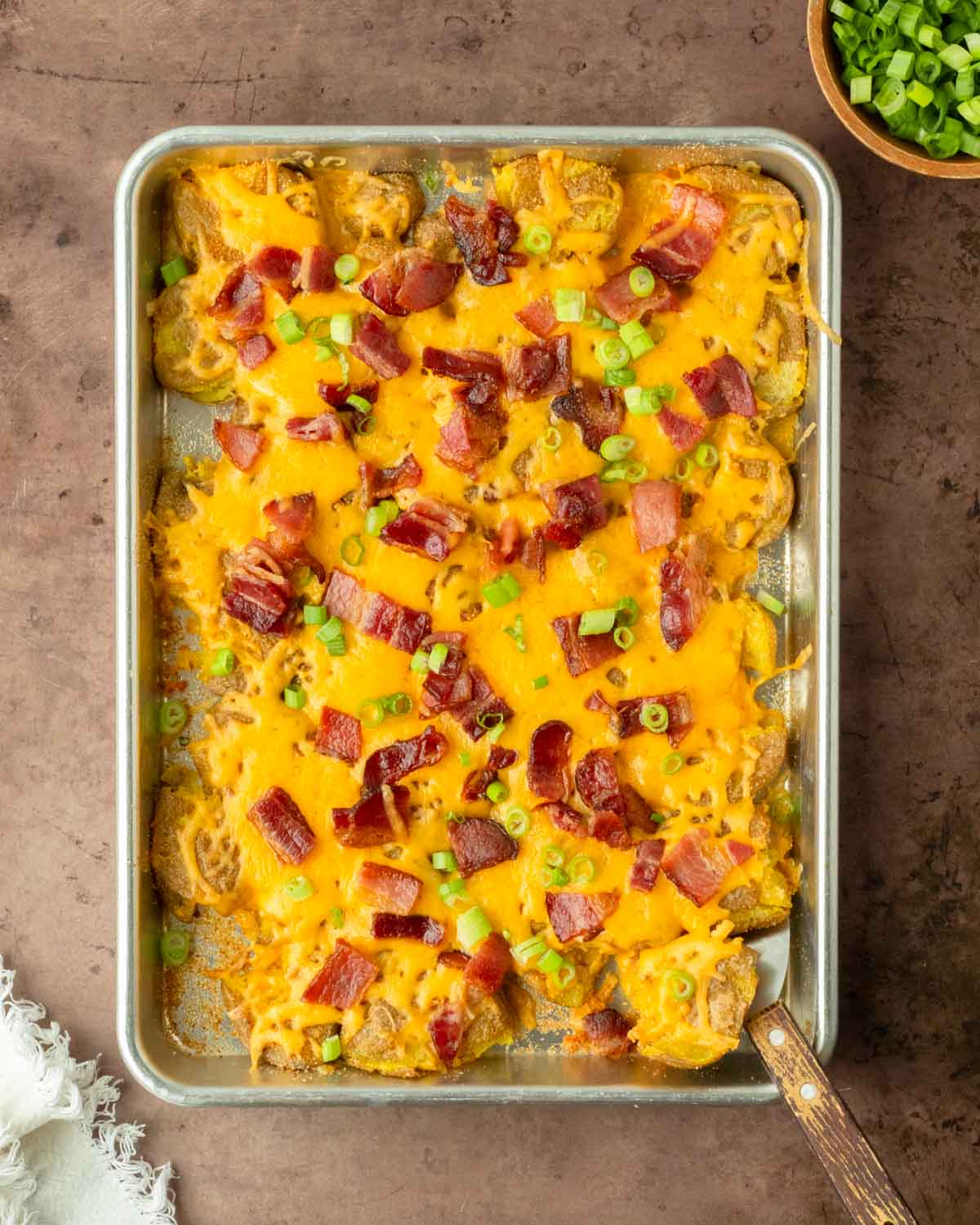 These twice baked smashed potatoes are everyone's favorite classic summer side dish made with crispy smashed potatoes baked on a sheet pan and topped with cheddar cheese and bacon. This recipe is perfect for a weeknight dinner side but also great to serve to a crowd.