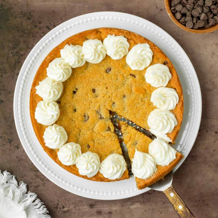 This homemade cookie cake is a thick and chewy chocolate chip cookie with a soft, chewy center and thick crisp edges perfect to serve to a crowd or enjoy as dessert with your family.