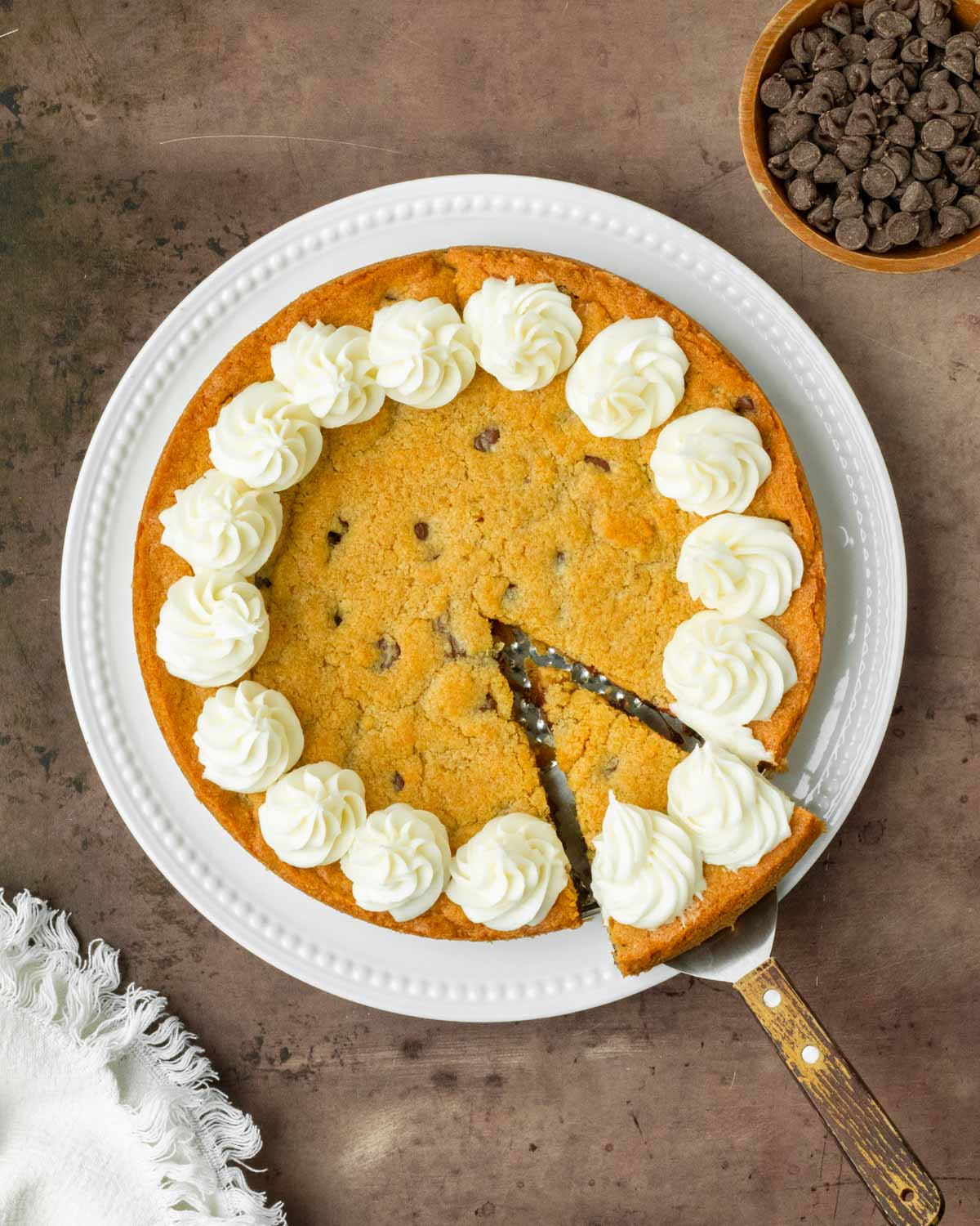 This homemade cookie cake is a thick and chewy chocolate chip cookie with a soft, chewy center and thick crisp edges perfect to serve to a crowd or enjoy as dessert with you family.